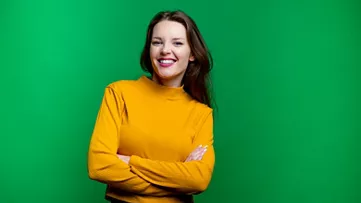 Mulher jovem sorrindo em frente a um fundo verde